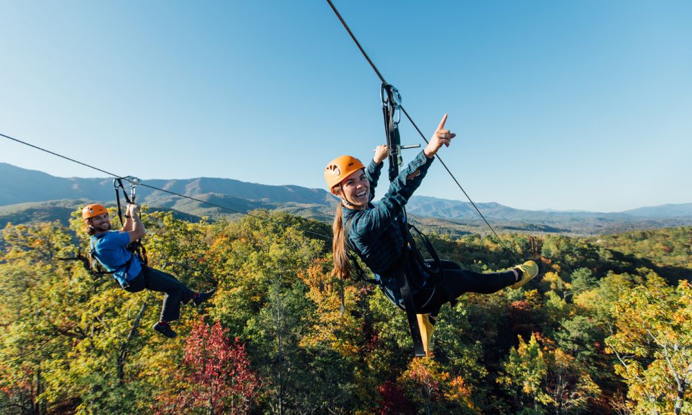 couple ziplining side by side during fall in the smoky mountains