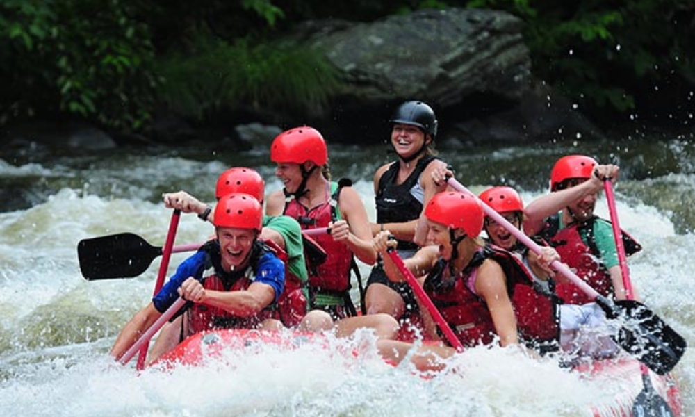group of people smiling while going through a rapid on a whitewater rafting trip