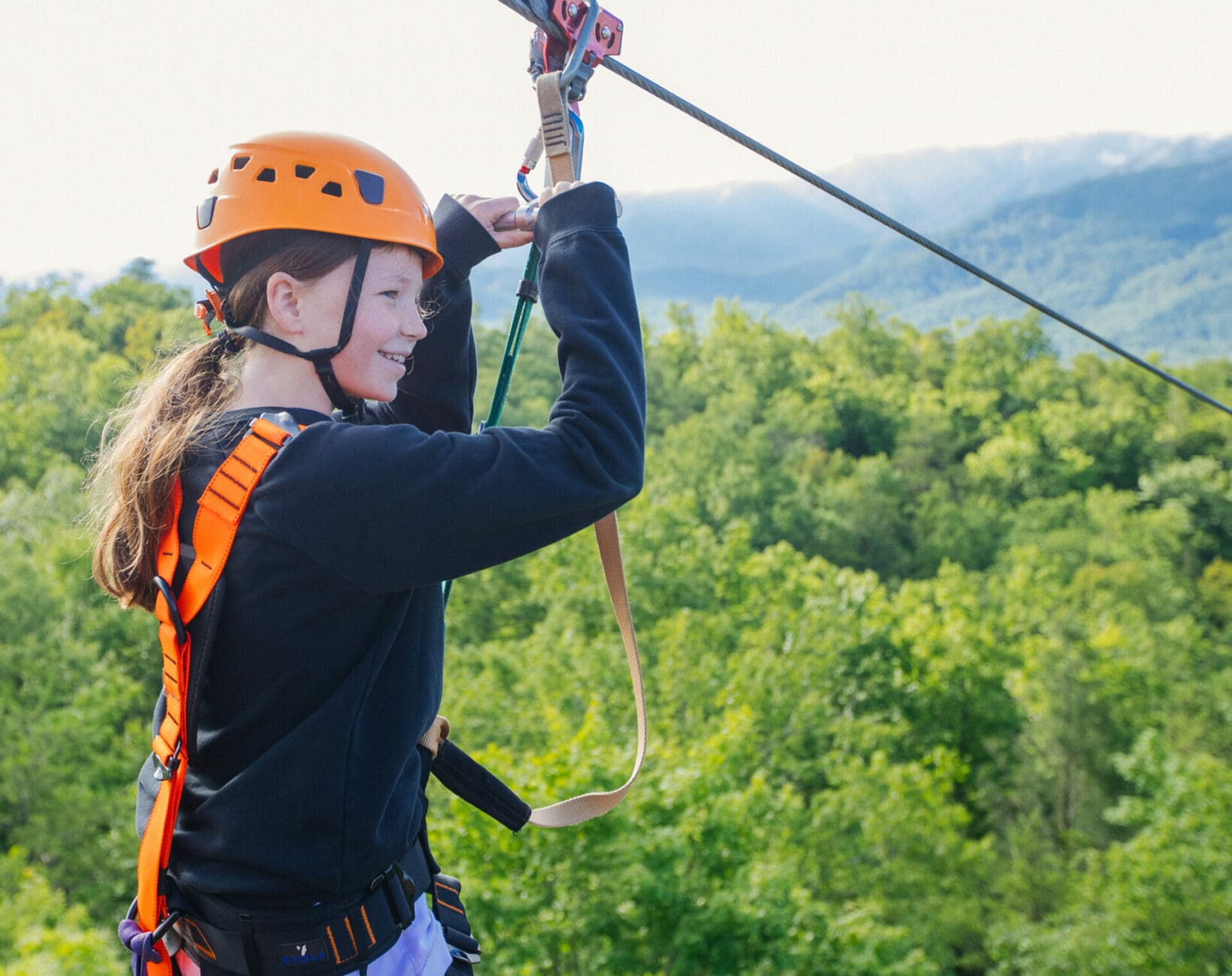 Smiling young girl riding a zipline at CLIMB Works Smoky Mountain